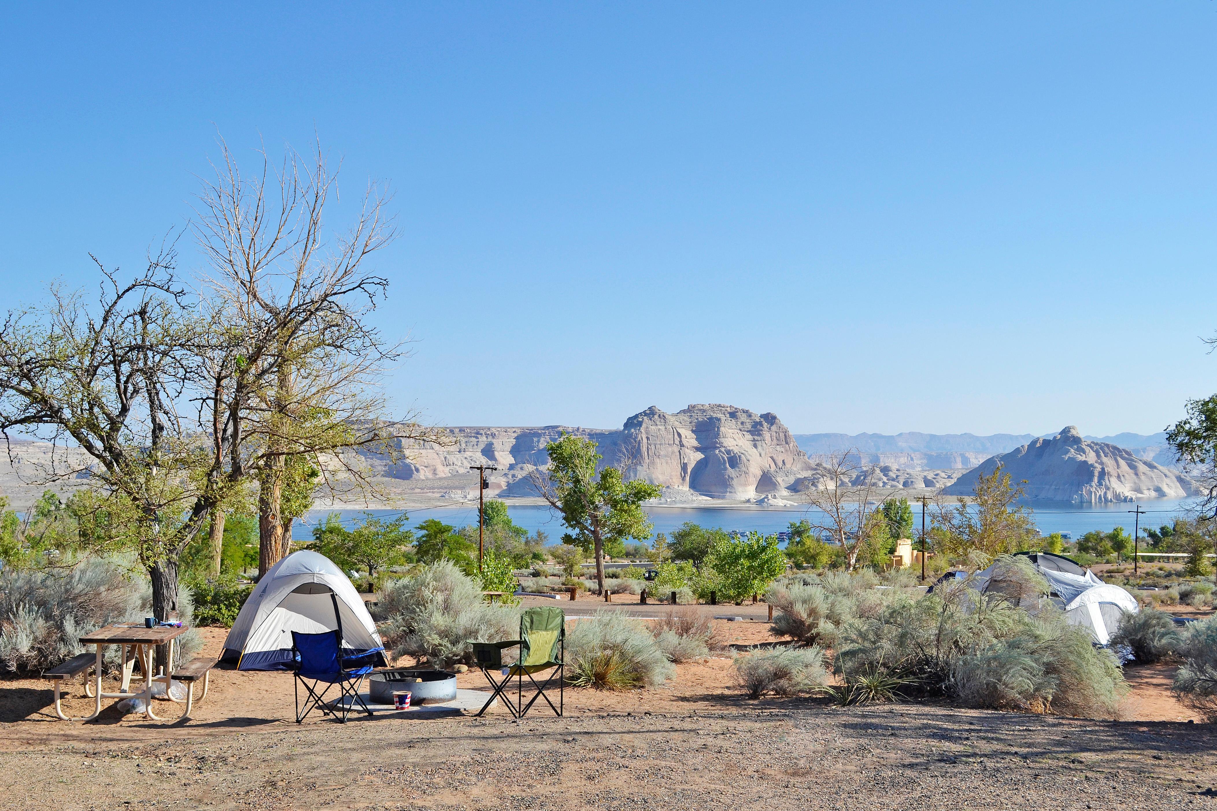 Two tents with picnic tables and grills. Lake Powell in background.