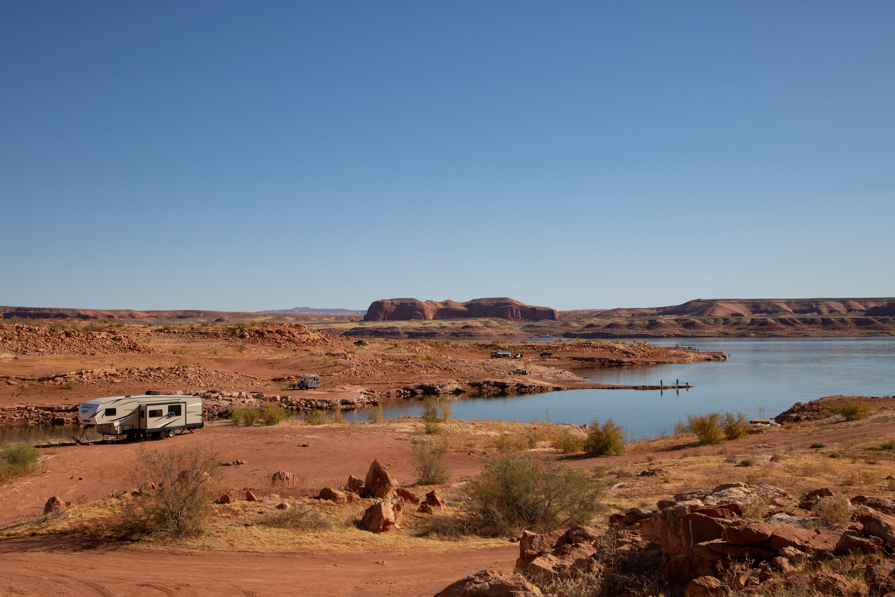 A few RVs parked next to the water's edge on a sandy beach