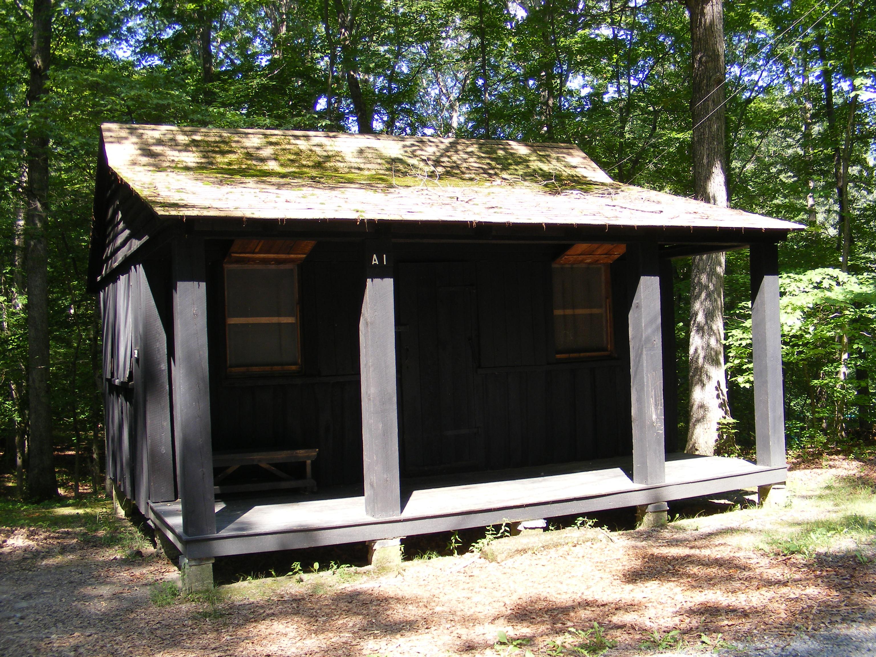 Wooden cabin with a porch and screen windows on a sunny day
