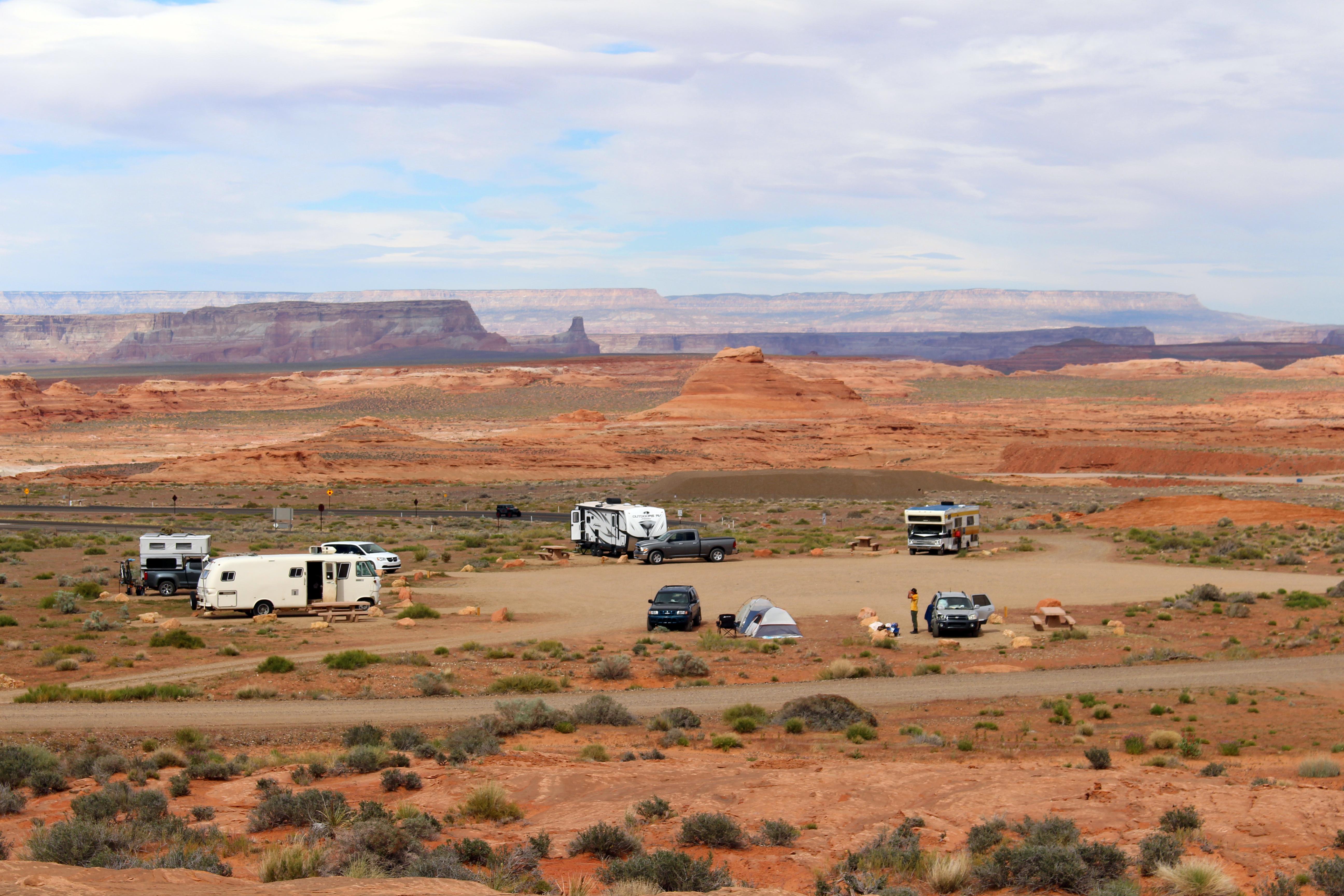 Twenty-one campsites on dirt grounds with sandstone cliffs above.