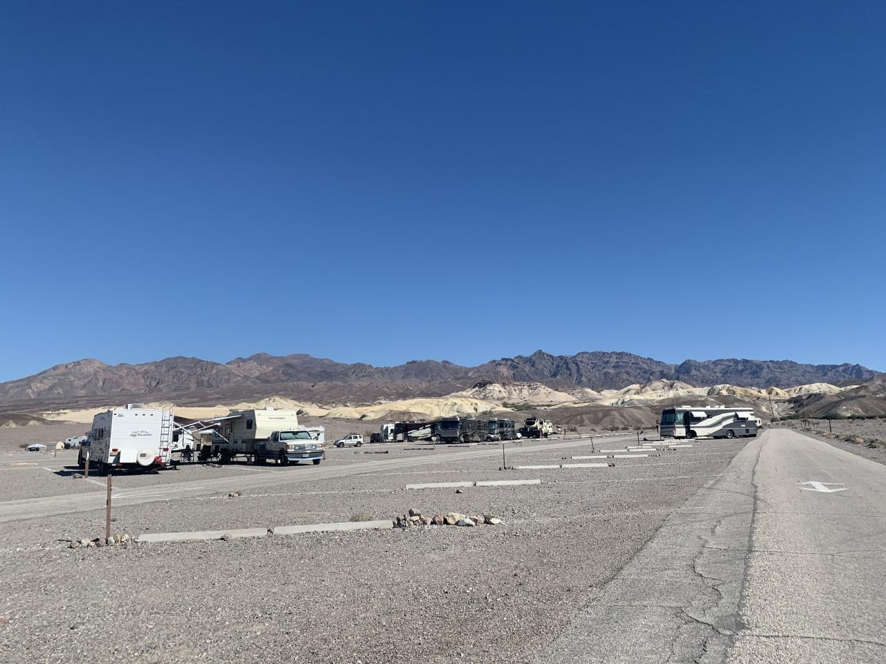 a roadway through gravel with RVs parked at spots marked by cement curbs