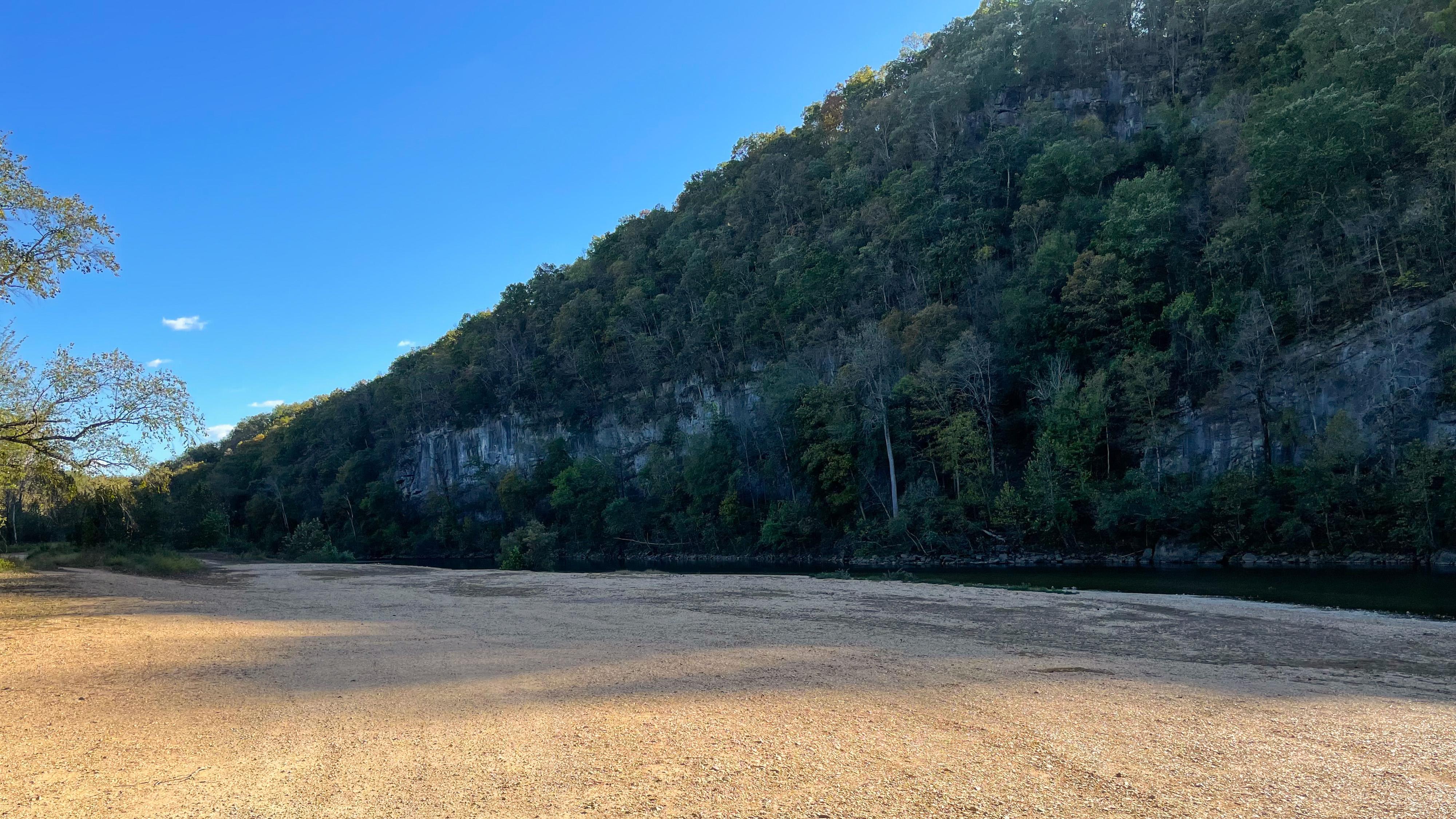 A large gravel bar across the river from a massive bluff.