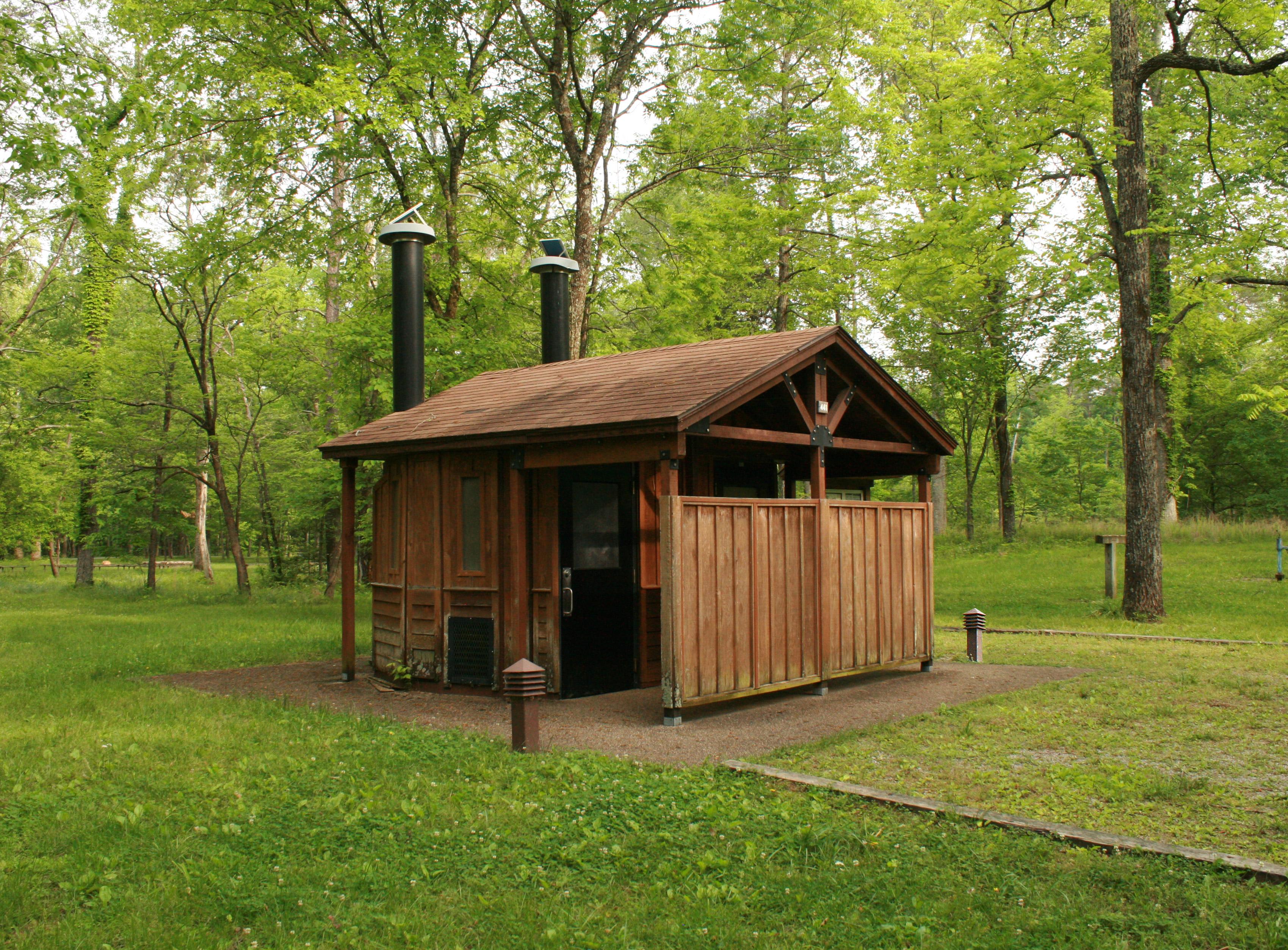 Exterior view of the roofed wooden restroom facility, with pit toilets.