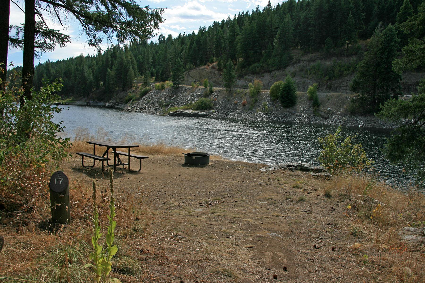 campsite with picnic table and fire pit, with view of river in background