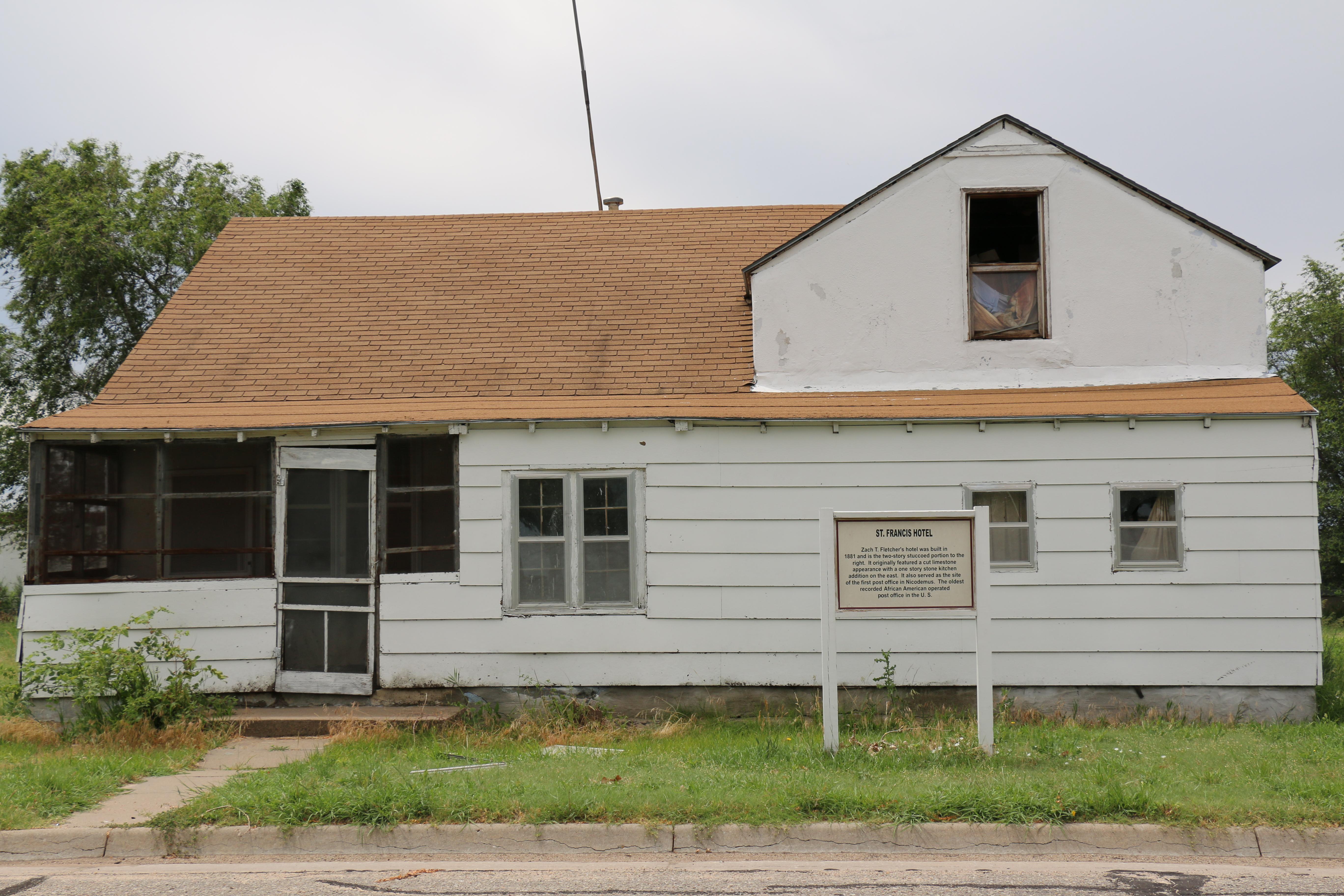 White frame with a second story gable on the right side, tan roof, and small screened porch.