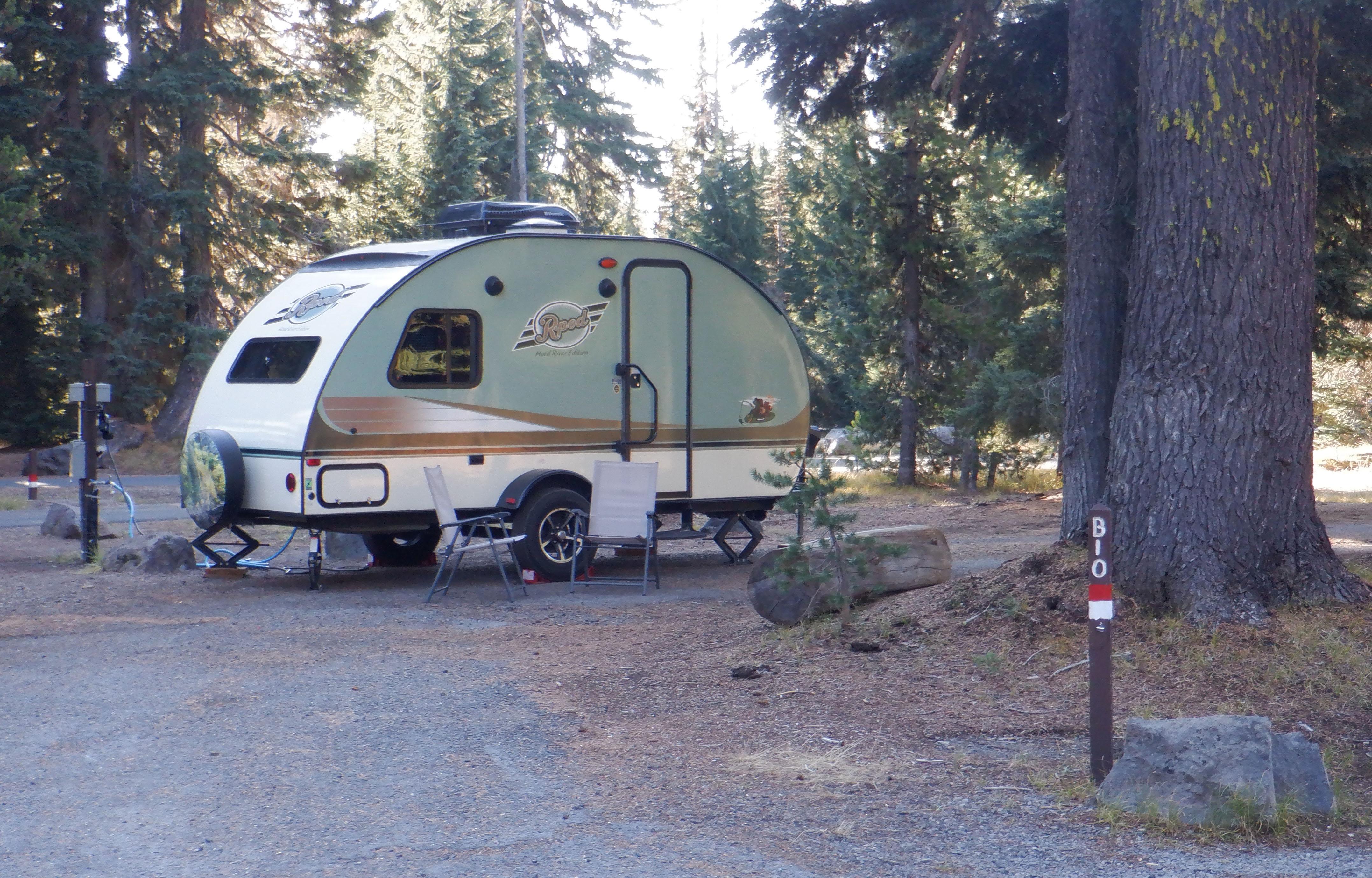 a small half moon shaped light green trailer parked in campsite # B10