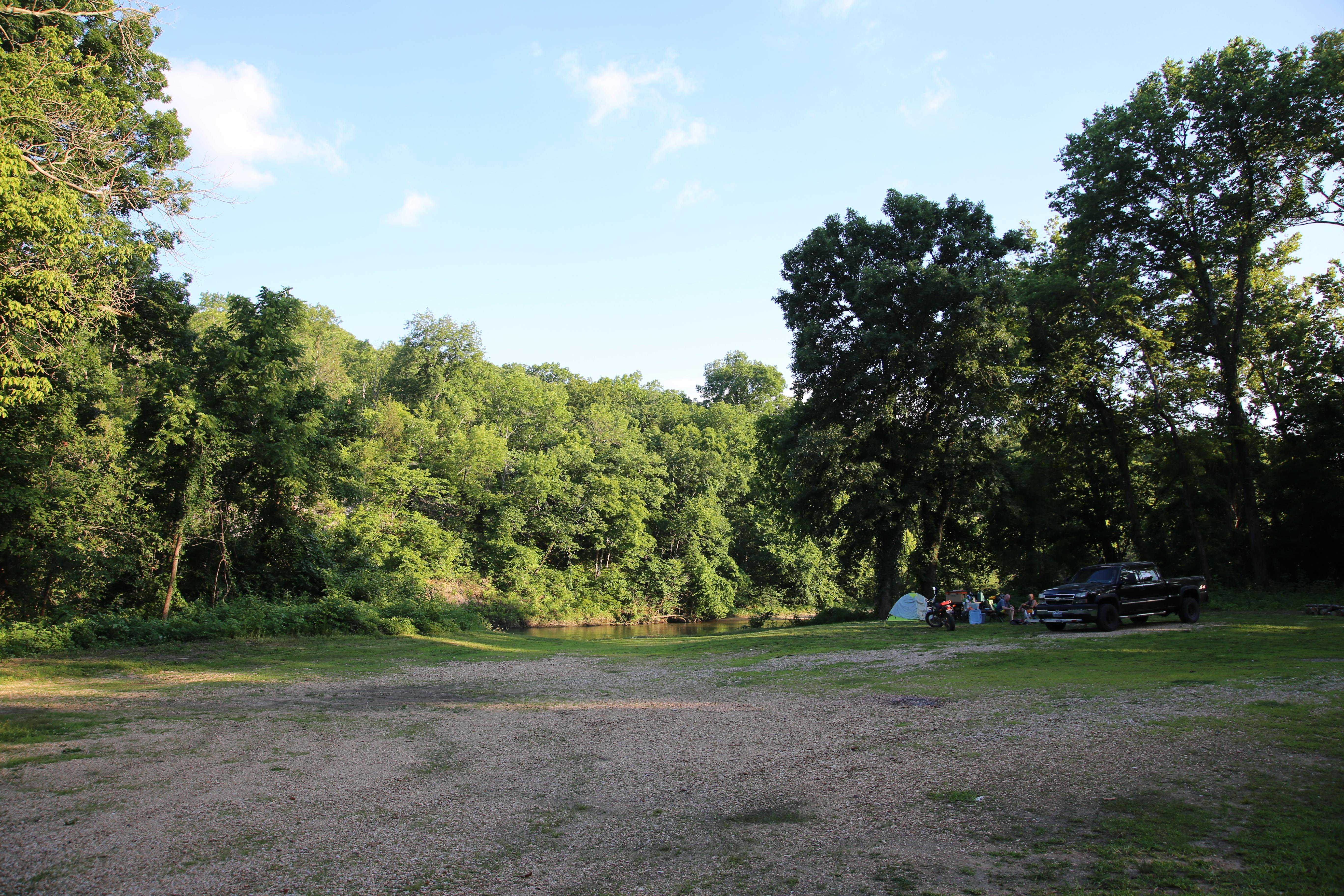 Two men enjoy their campsite near the river's edge.