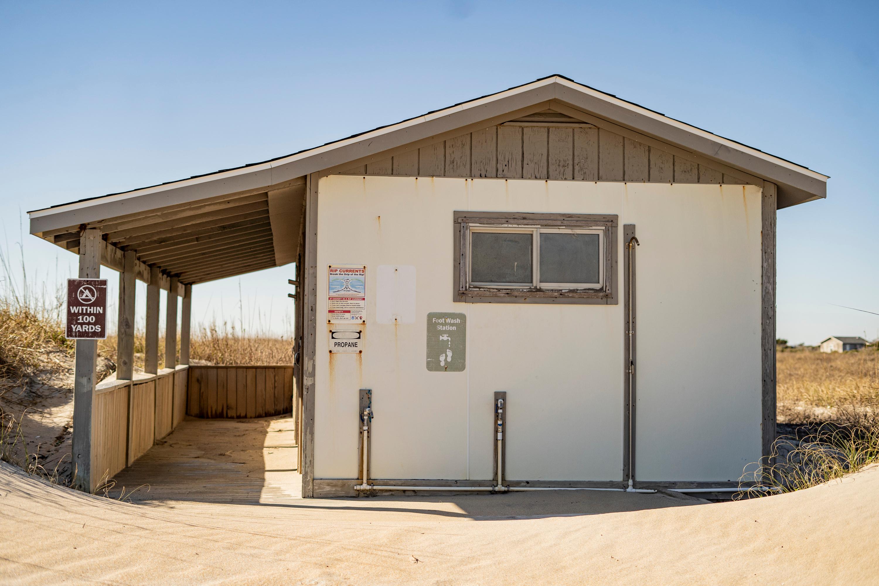 A white building with a shaded walk way in the sand.