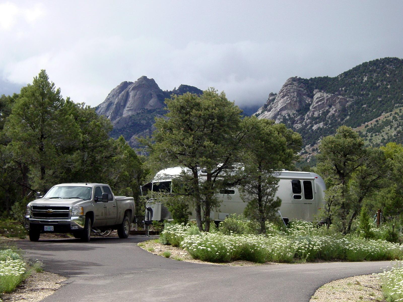 A truck with an Airstream trailer on a paved pad with mountains in the background.