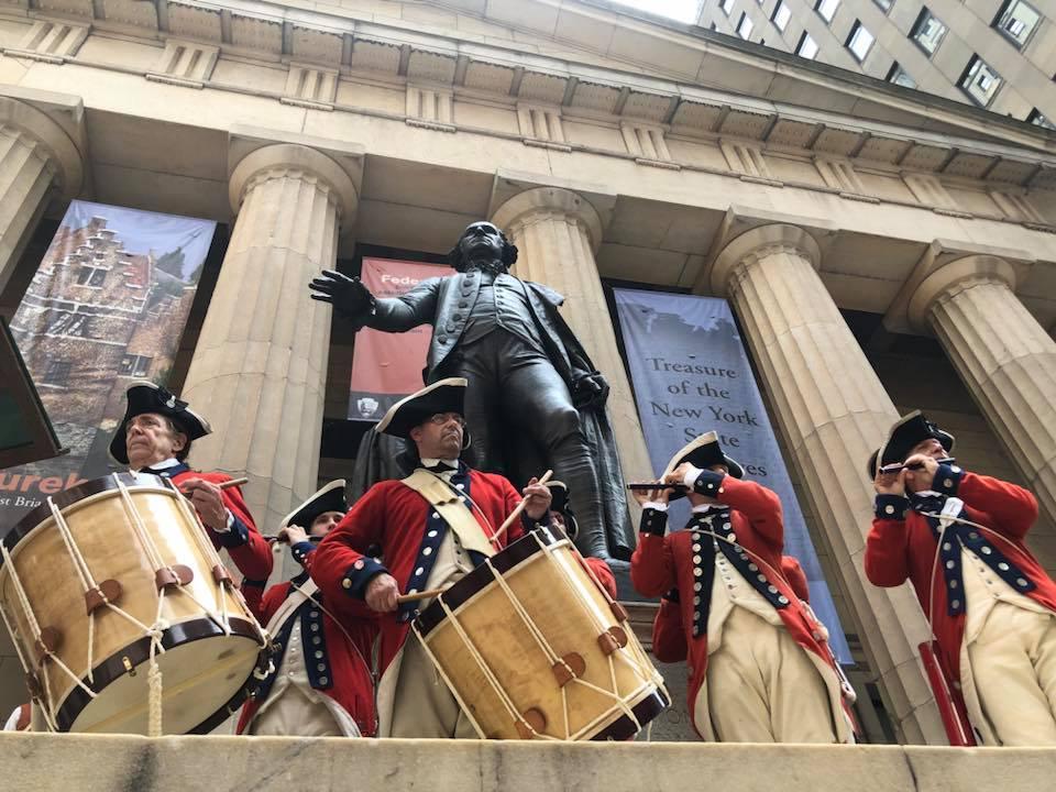 Five men dressed in Revolutionary War outfits play fife and drums
