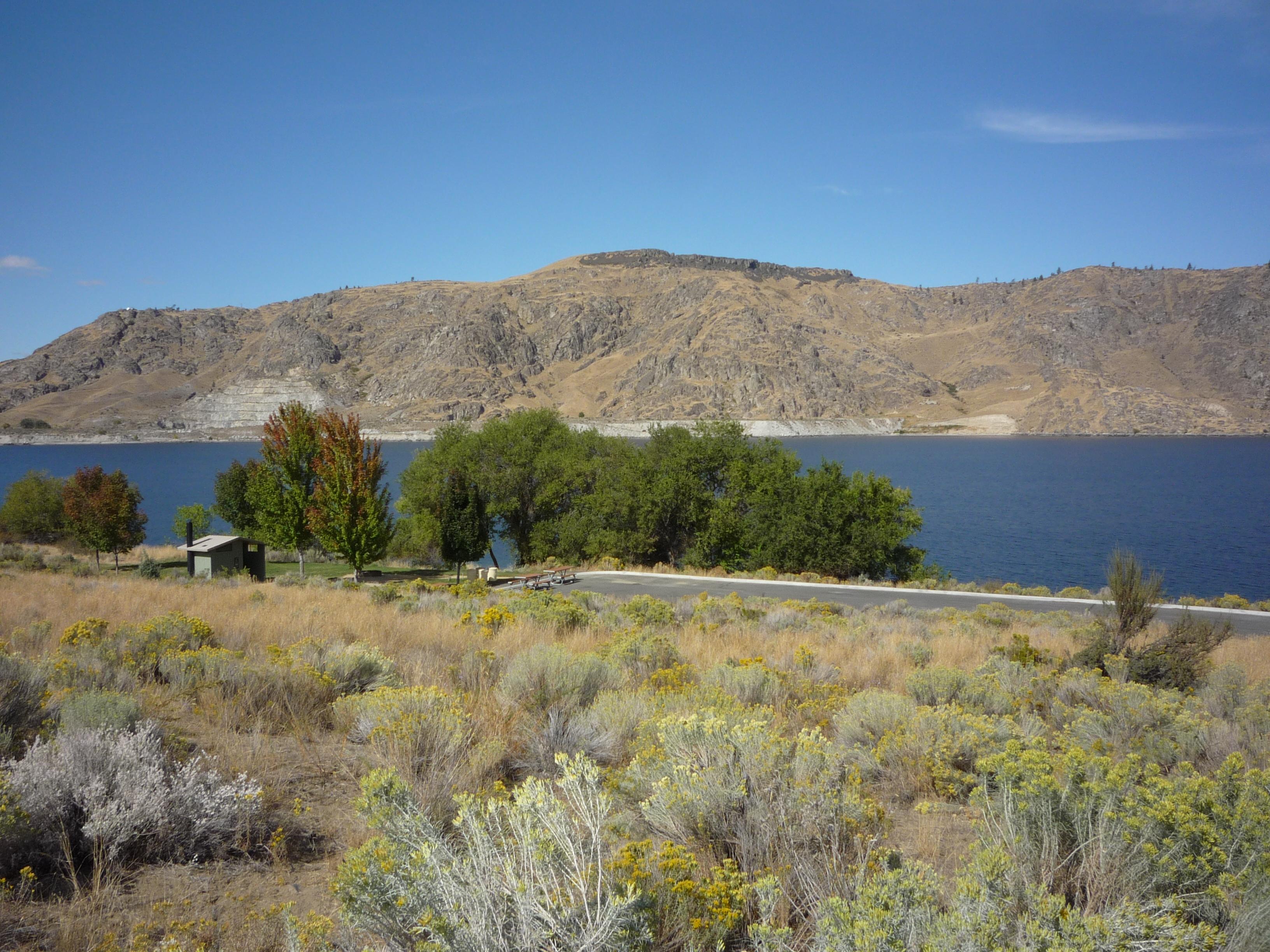Looking down on the group site with a bathroom and picnic tables, adjacent to paved parking.