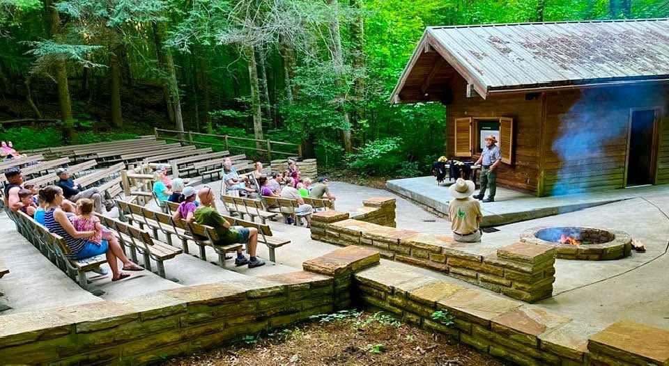 Park Ranger standing on stage at the campground amphitheater for a park program with an audience.